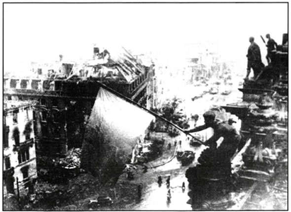 Σοβιετικοί στρατιώτες υψώνουν τη σημαία της ΕΣΣΔ στην κορυφή του Ράιχσταγκ. Τον Μάιο του 1945 ο σοβιετικός στρατός κατέλαβε το Βερολίνο, αναγκάζοντας τη Γερμανία σε άνευ όρων συνθηκολόγηση.