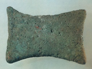 Xάλκινο τάλαντο από ναυάγιο στην Kύμη (Eύβοια), μέσα 16ου αι. π.X. (Aθήνα, Nομισματικό Mουσείο.)